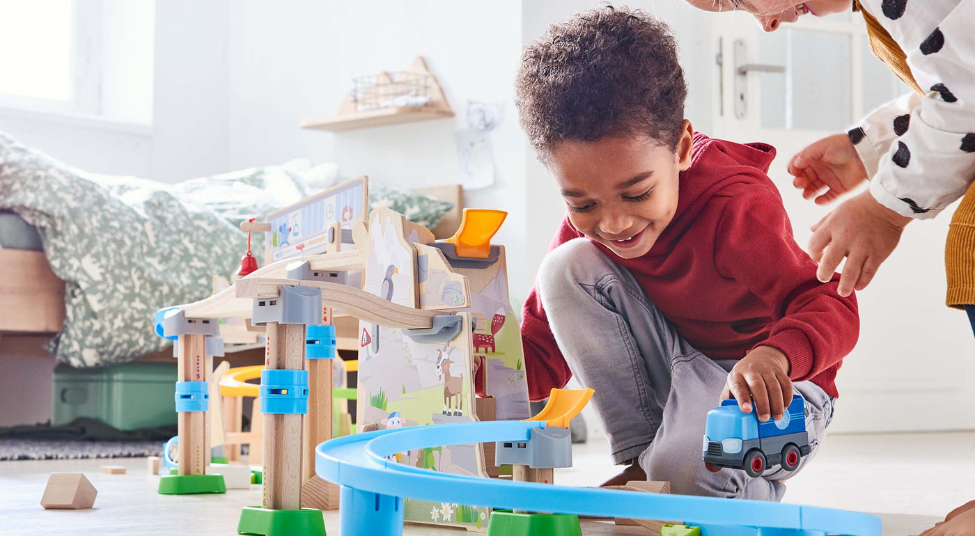 A kid is playing with a Kullerbu Track Set from HABA USA.