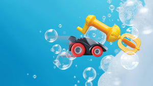 Toy race car with a bath whisk amongst bubbles on a blue background.