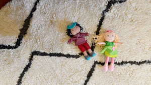 Overhead view of HABA William and Mali 12" soft dolls laying on a furry rug