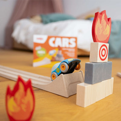 A toy car on a ramp with wooden blocks stacked ahead, featuring flame and target designs.