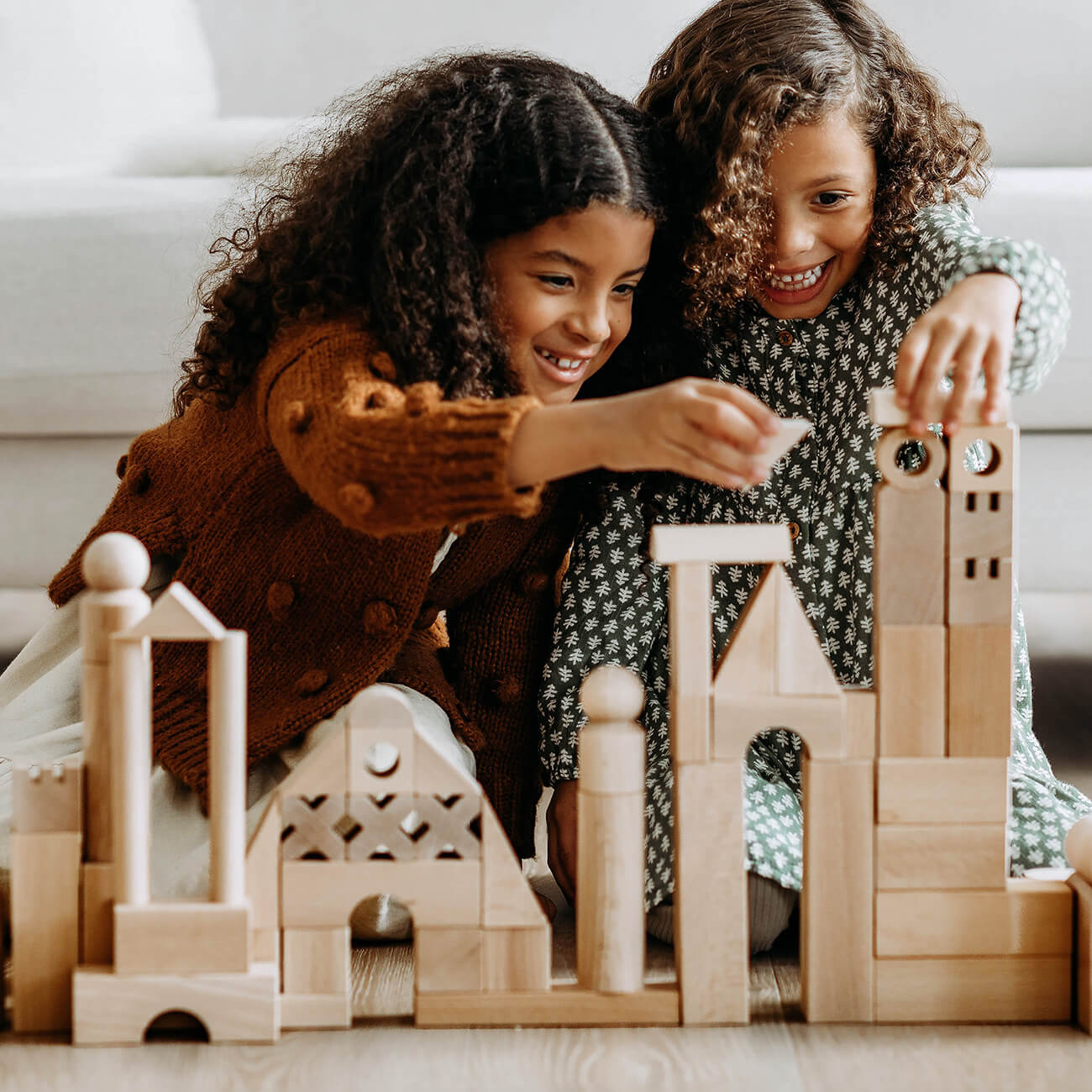 Two girls working together building a city out of HABA wooden blocks