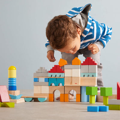 Young boy bending over a constructed castle of colored building blocks