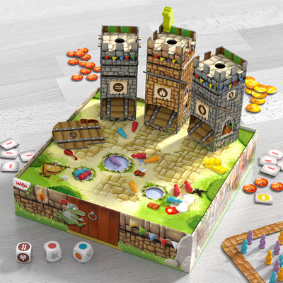 A colorful board game with castle towers, knight pieces, dice and coins on a wooden table.