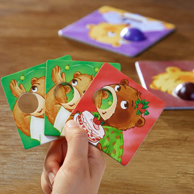 Closeup of hand holding 2 green bear cards and 1 red bear card