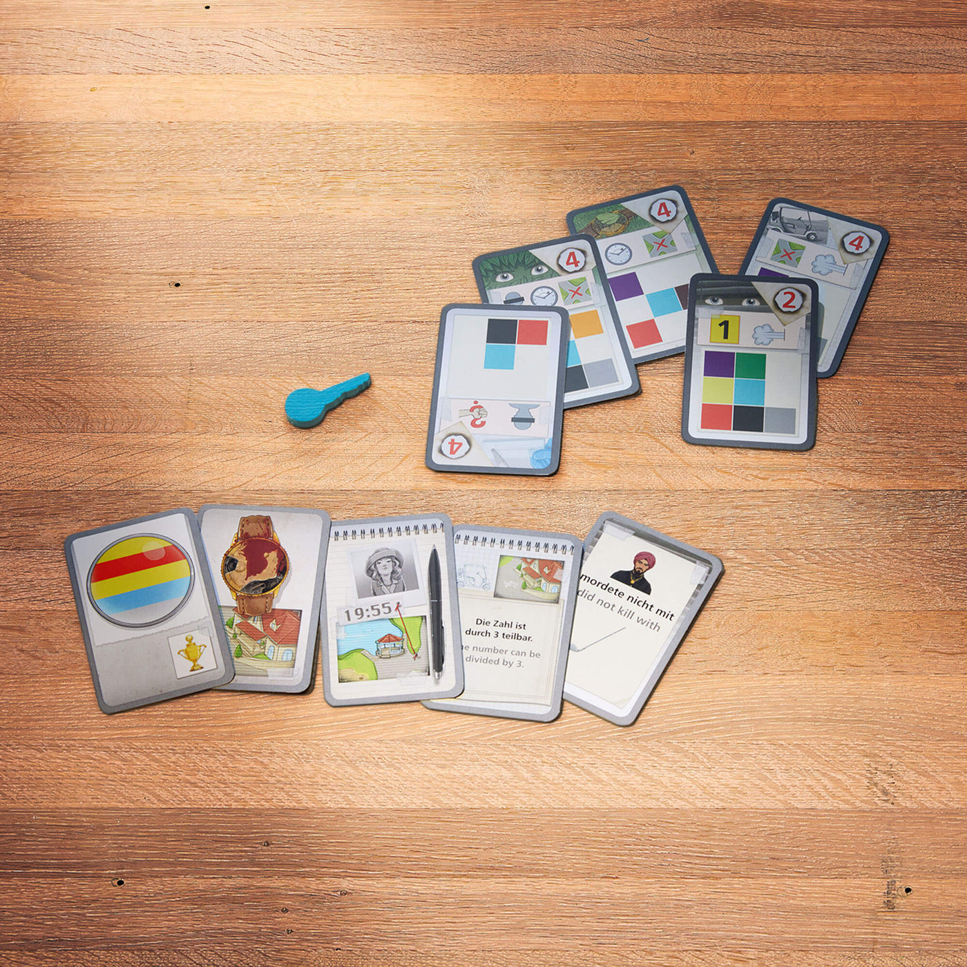 A set of game cards with symbols and colors spread out on a wooden surface, accompanied by a blue key game piece.