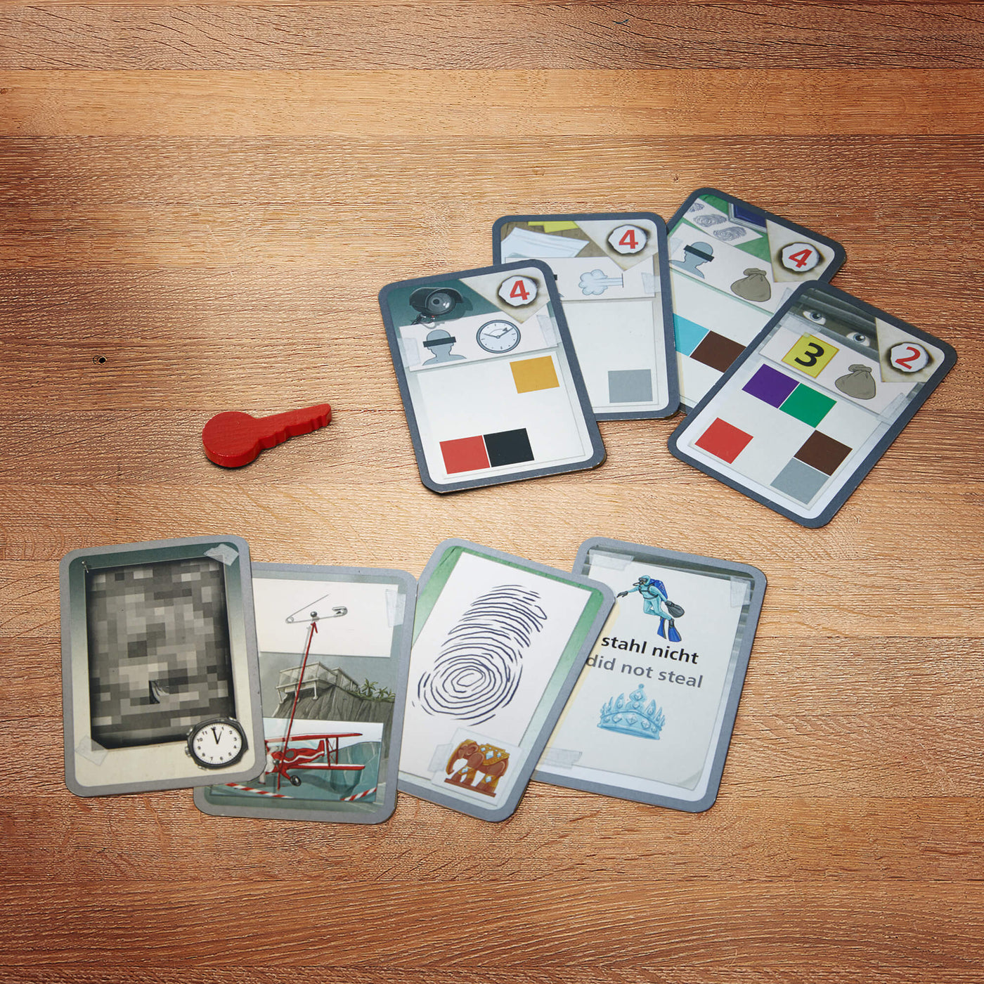 The Key game cards with various designs and a red key-shaped token on a wooden surface.