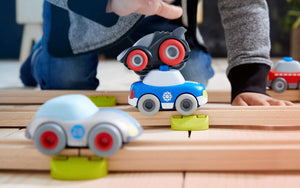 Close up of Kullerbü cars on a wooden track and a child's' hands in the background