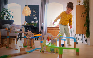 girl in a living room standing behind a large marble run track set up in a holiday scene