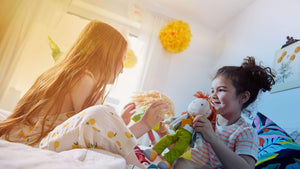 Two girls on a bed playing with HABA soft dolls