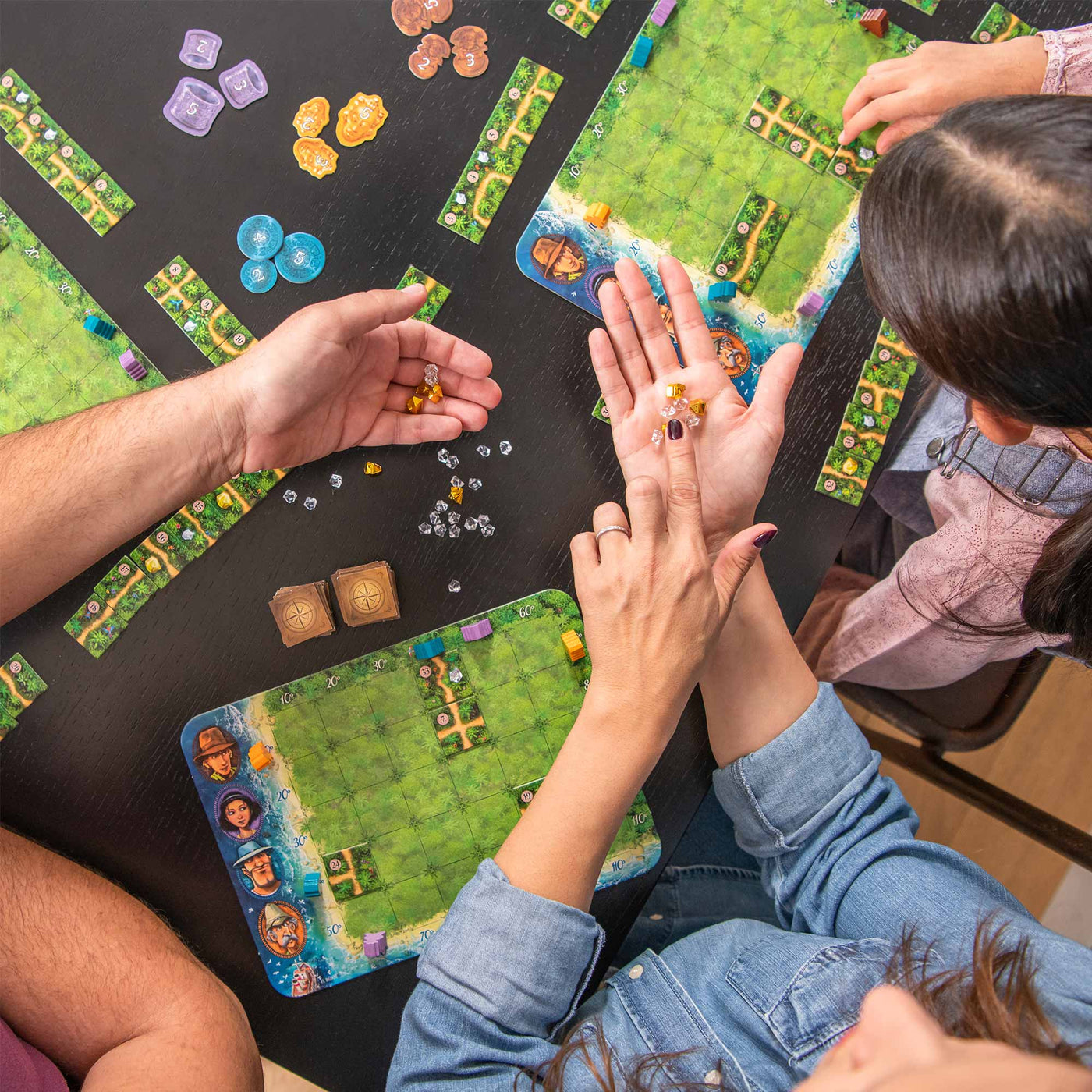 A tabletop scene of people playing Karuba board game, showcasing colorful game pieces and strategy boards.