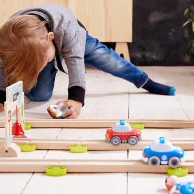 Child kneeling on the floor playing with Kullerbu track set