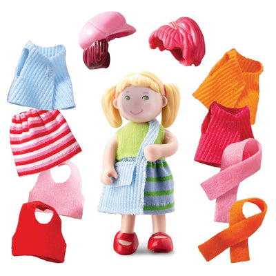 Little Friends Feli with multiple accessories including pink hat, pink hair, blonde hair, green shirt, striped blue and green skirt, blue bag, orange shirt, red shirt, pink scarf, orange scarf, red shirt, pink shirt, pink/red/white striped skirt, and blue shirt