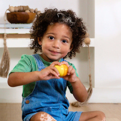 Boy sitting and playing with a yellow wooden Musical Egg