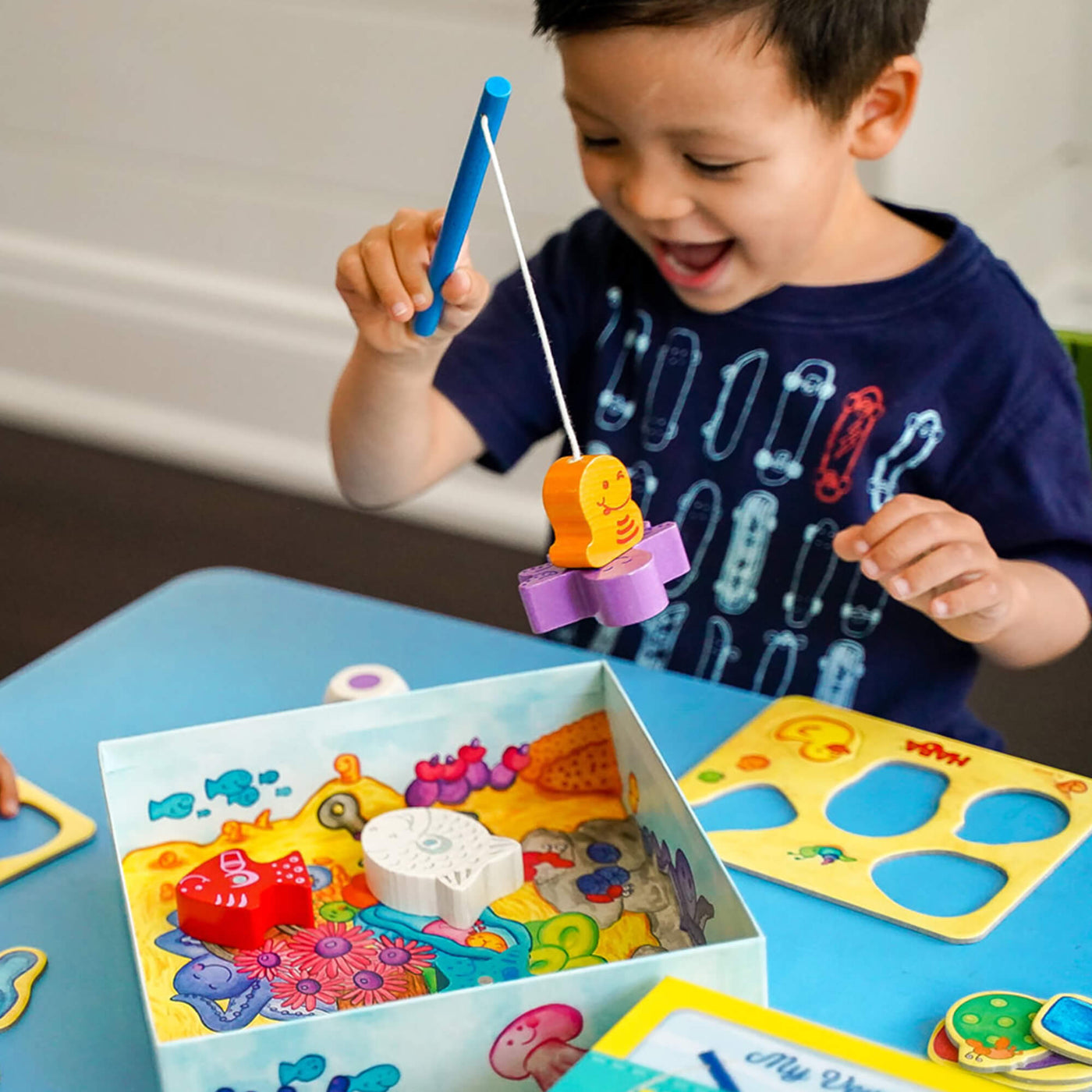 Laughing boy holding a toy fishing rod playing My Very First Games - Here, Fishy, Fishy! Magnetic Game