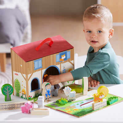 Young boy playing with HABA's Play World on the Farm on a living room table